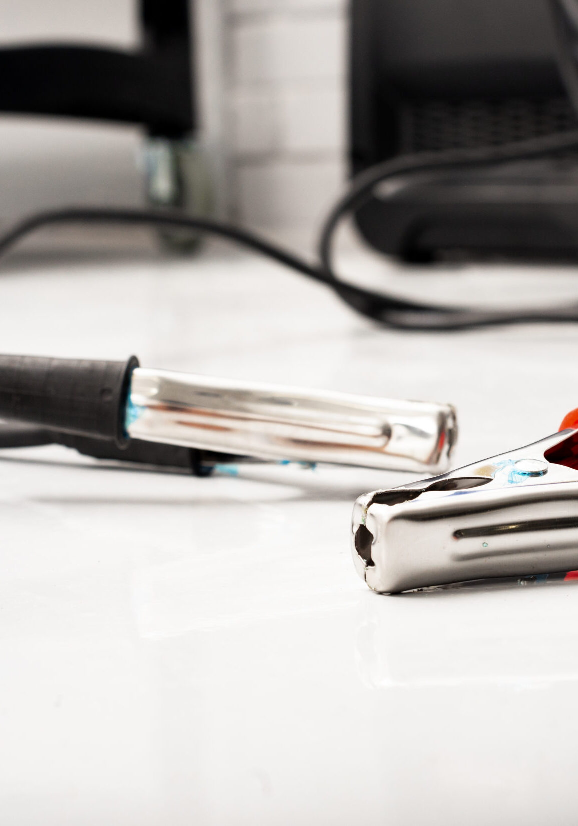 red and black clamps for charging battery car with electricity lying on the floor in car repair garage