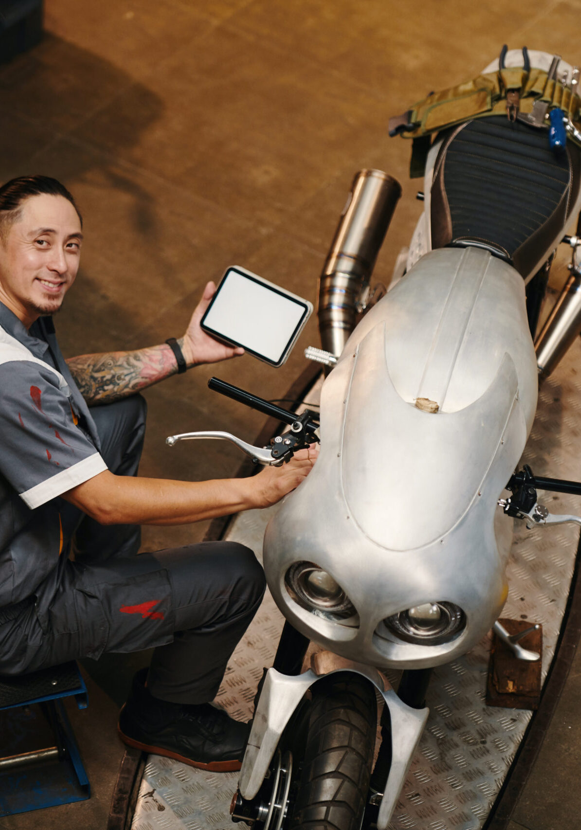 Smiling repairman using application on tablet computer when examining motorcycle